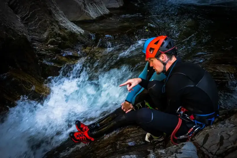 Canyoning guide briefing two guests beside a mountain stream