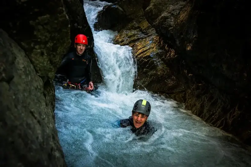 Two people laughing in a canyon pool after a jump