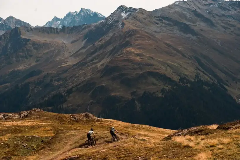 Mountain biker riding with dramatic glacier peaks in the background