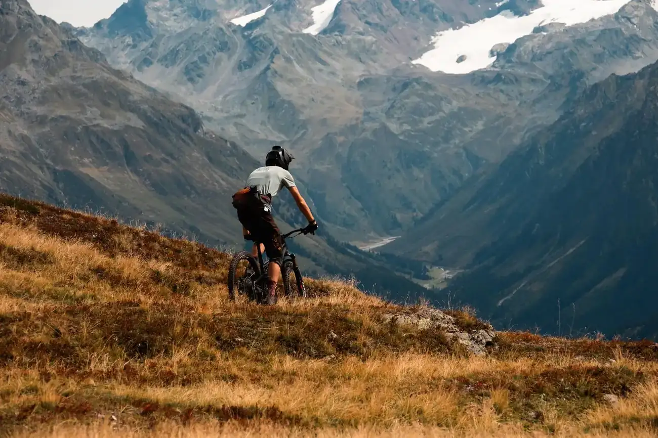 Mountain biker looking out over an alpine valley from a mountain ridge